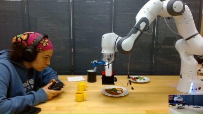 Maya Keely works with a robot as it is programmed to respond to input to create a pizza. Photo courtesy of Maya Keely.