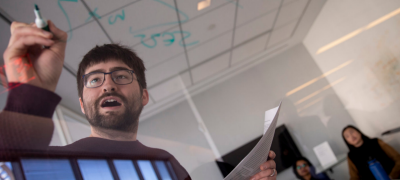 Professor teaching students at a whiteboard